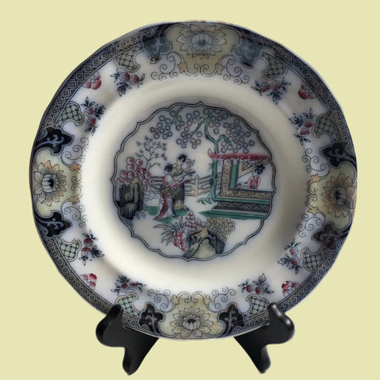Decorative ceramic plate with intricate designs on a stand against a white background