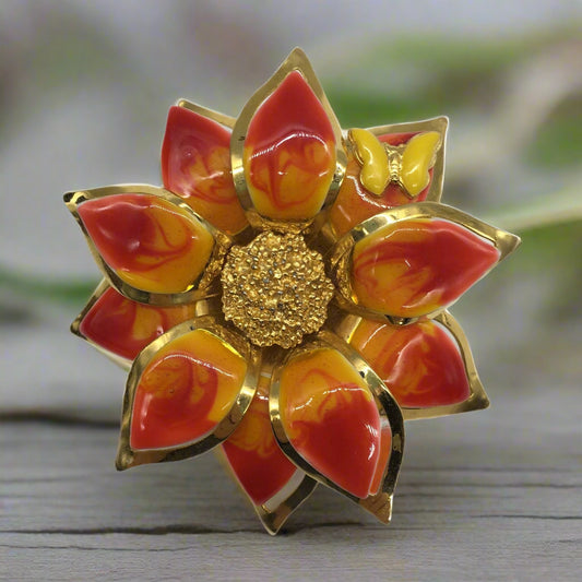 Decorative brooch with red, orange, and gold colors on a white background