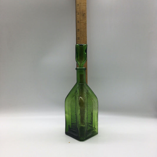 Green glass bottle with a wooden ruler for scale on a white background