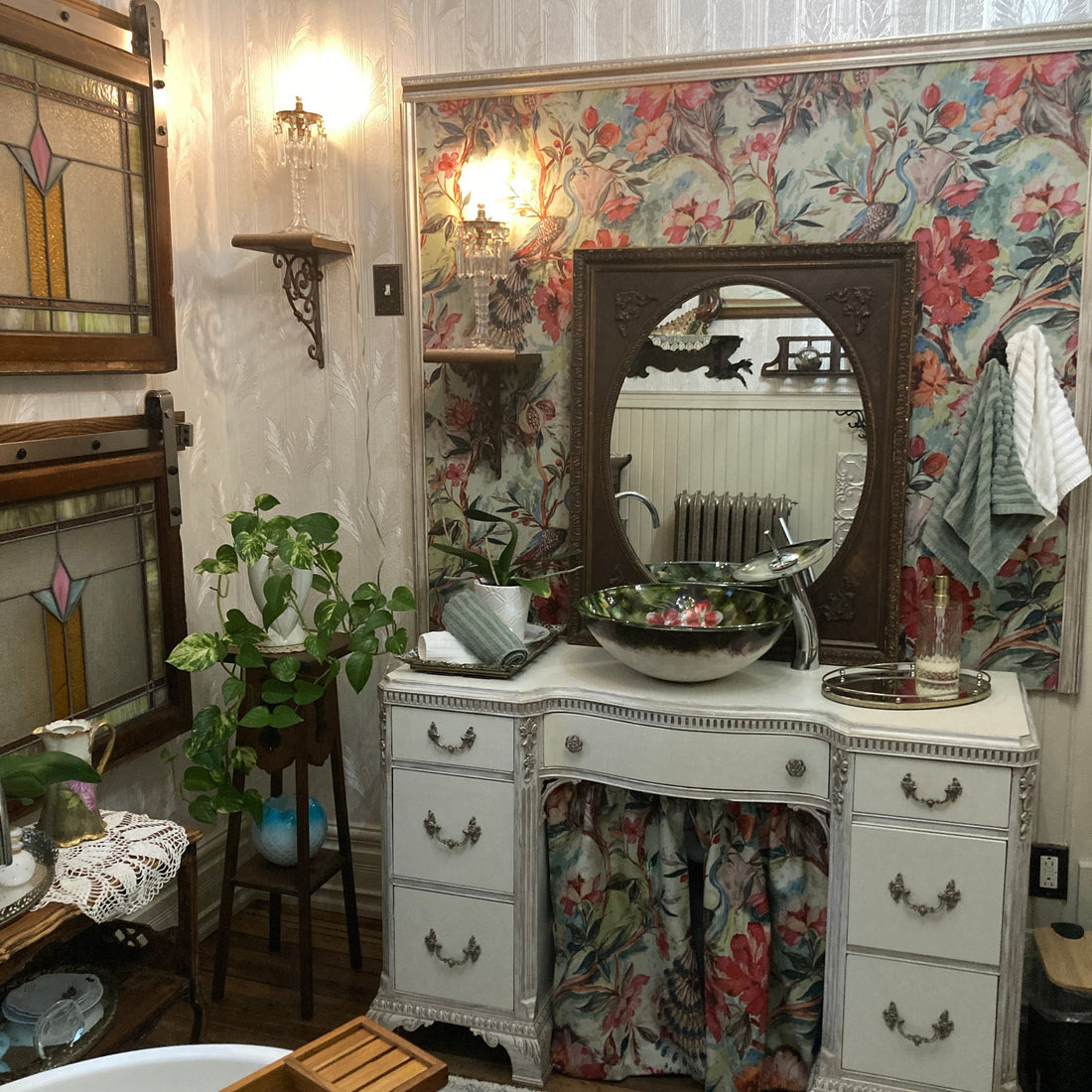 Antique white dressing table transformed into a bathroom vanity with a green floral vessel sink.
