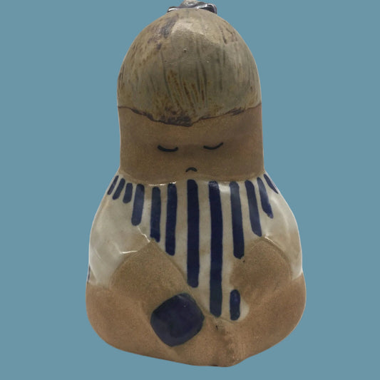 Ceramic figurine of a seated figure with blue accents on a white background