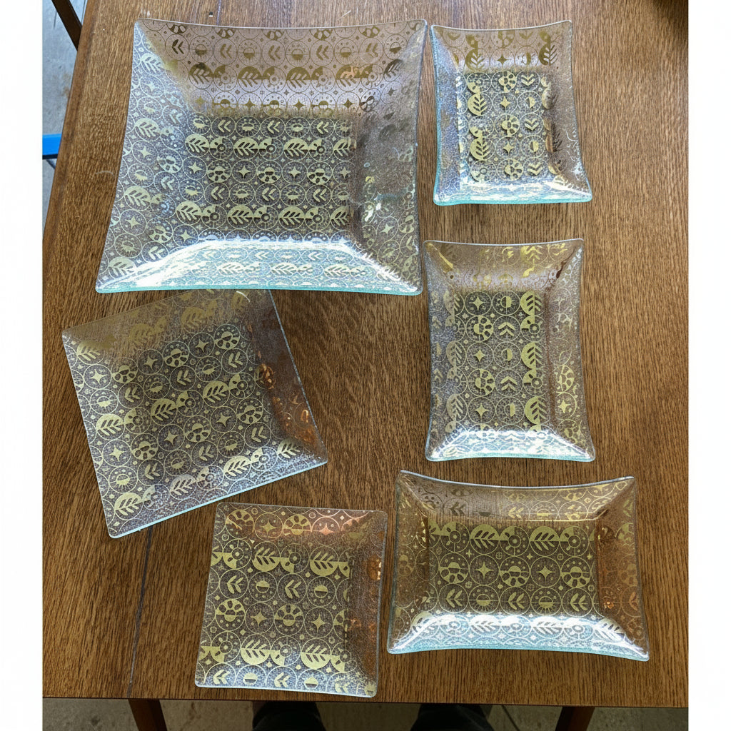 Set of decorative glass plates with gold patterns on a wooden surface