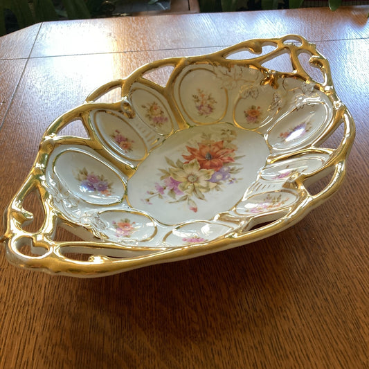 Decorative ceramic dish with floral patterns and gold trim on a wooden surface