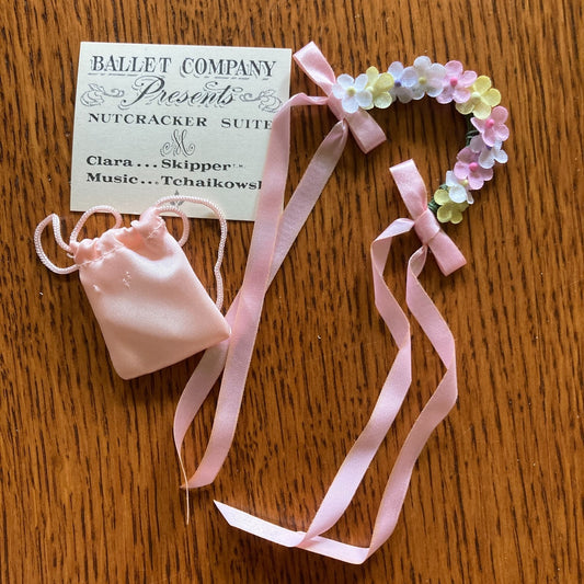 Pink ballet slipper and headband with floral accents on a wooden surface, featuring a 'Nutcracker Suite' card.