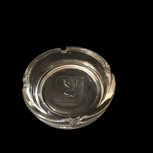 Clear glass ashtray with a logo on a black background