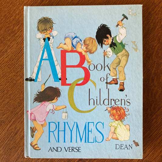 Book titled 'ABC Book of Children's Rhymes and Verse' with illustrations on a wooden surface